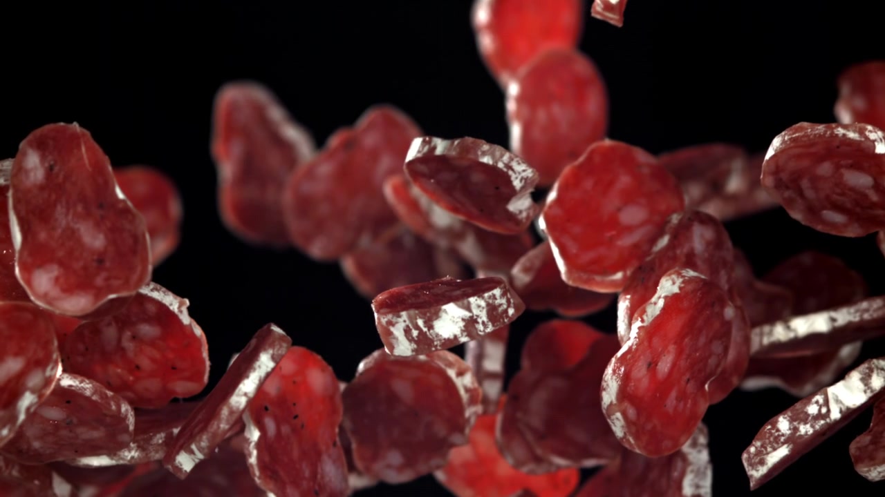 Slices of Salami Falling in Slow Motion on Black Background