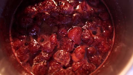 Beautiful strawberries slowly cooking in the small saucepan with steam hitting the lens, SLOMO