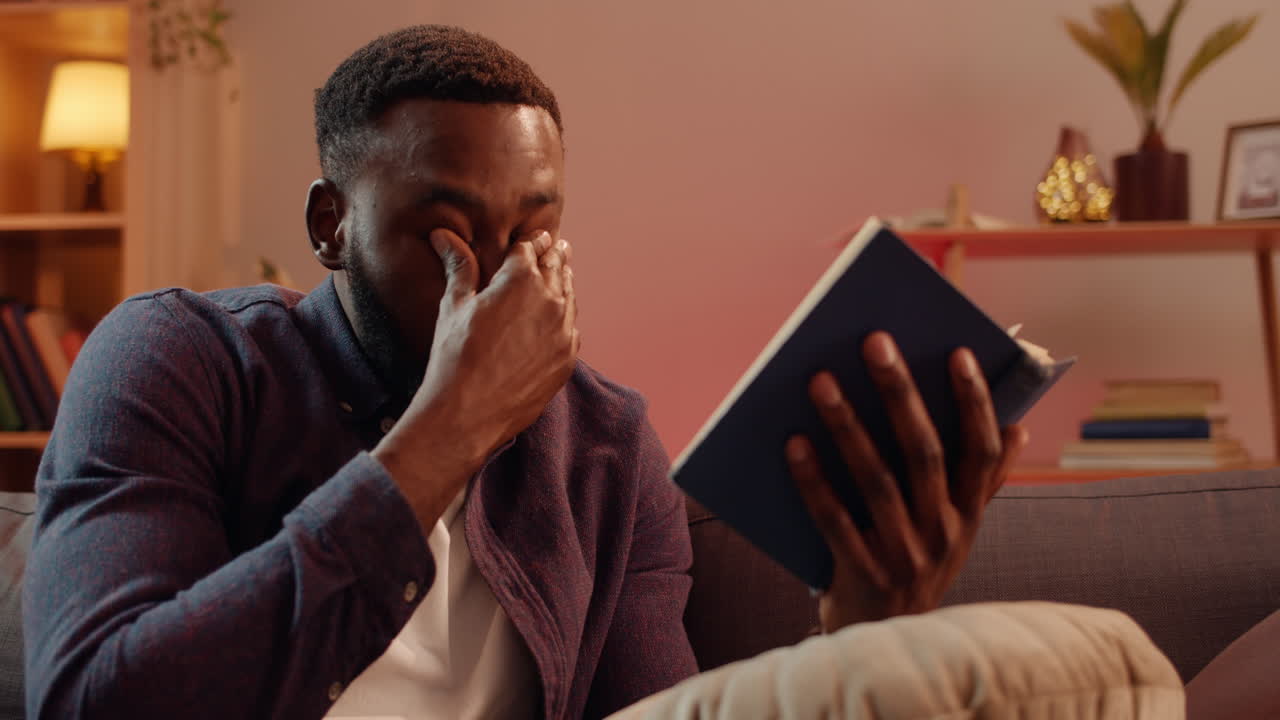 Man Crying While Reading a Book at Home