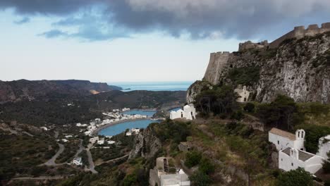 Sobrevuelo-Junto-A-Las-Murallas-Del-Castillo-De-Chora-Que-Revela-La-Bahía-De-Kapsali,-Isla-De-Kythira,-Grecia