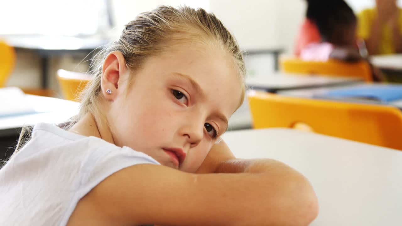 Ragazza triste sdraiata sul banco in classe
