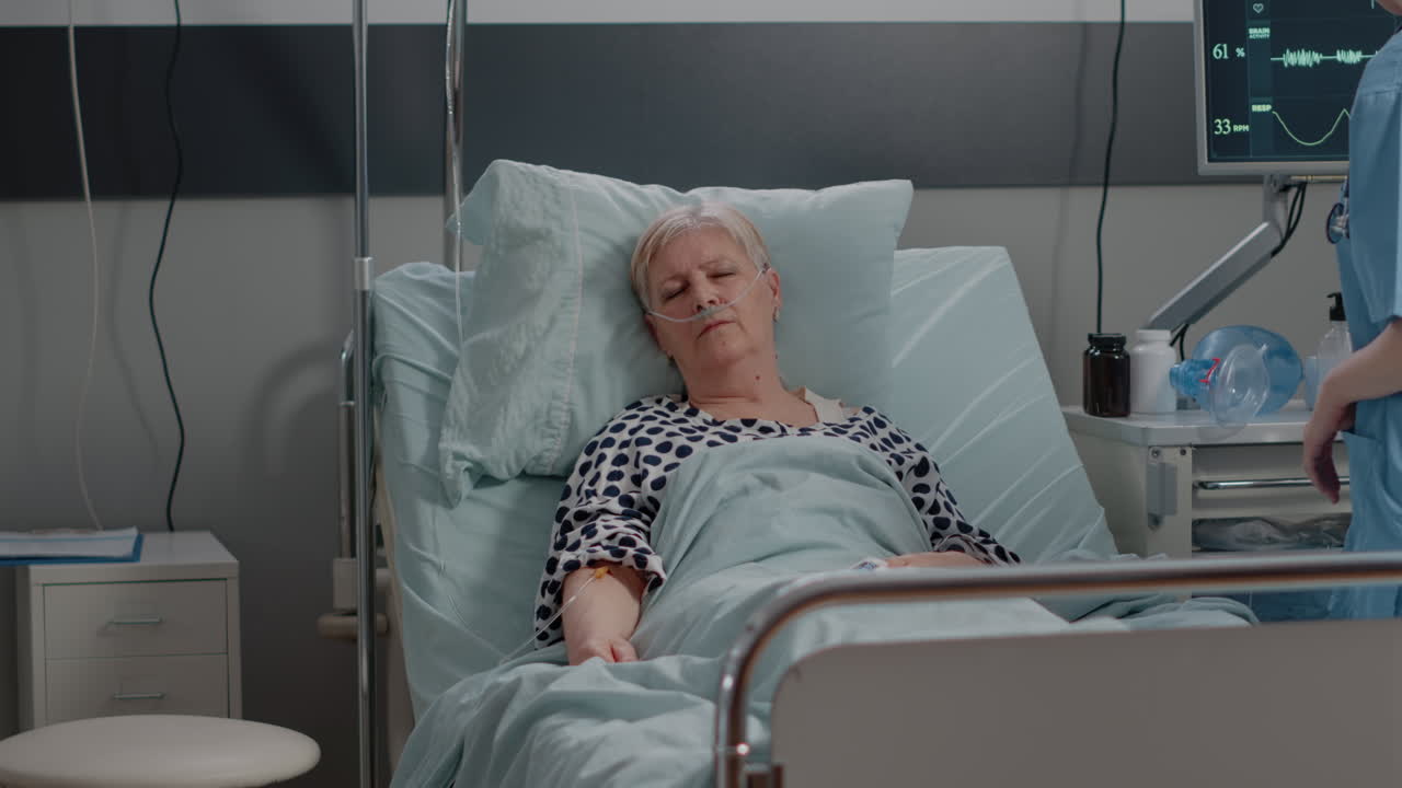 Elder woman with IV drip bag sleeping in hospital ward bed