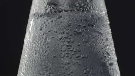 botella de vidrio con bebida fría espumosa