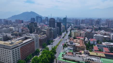 static aerial shot of santiago city center with tree-lined avenue, modern towers, and andes mountains in the distance