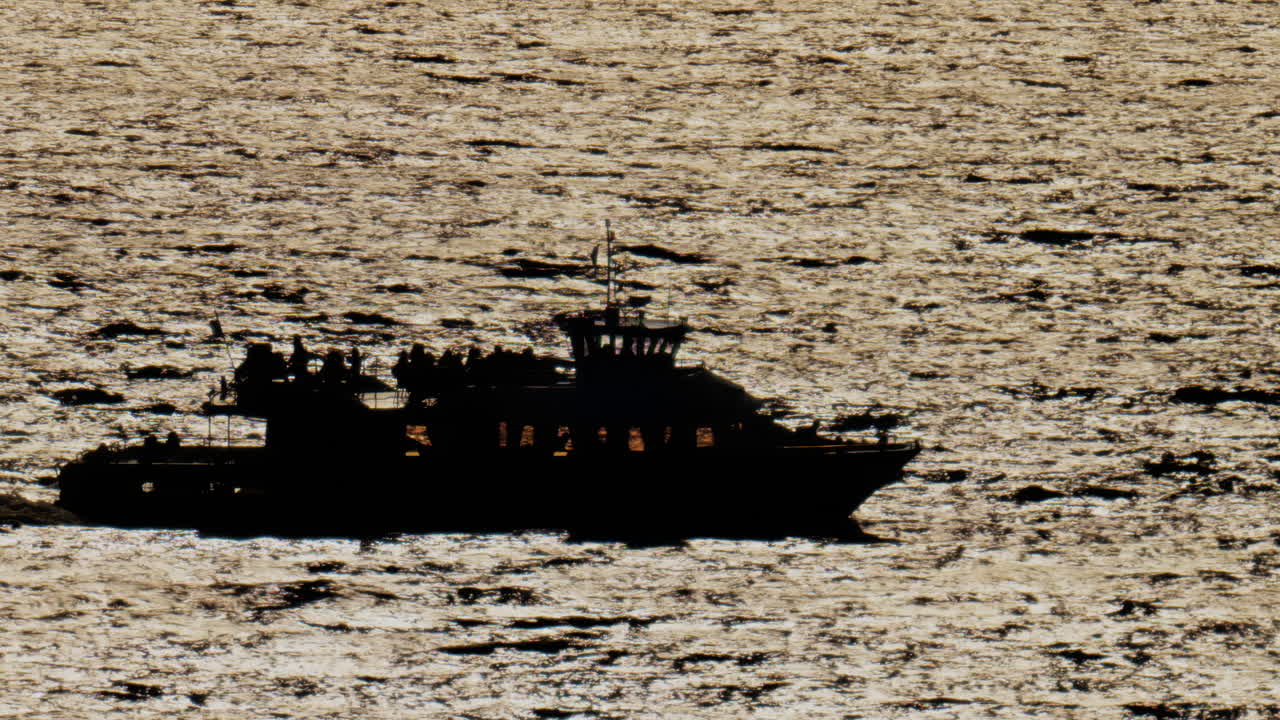 Blurred view of a boat filled with people moving on the sea on a sunny day