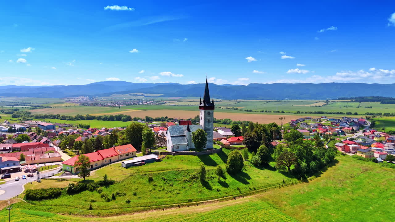 Church on the hill in the picturesque rural area. Drone footage in the countryside of Slovakia. Tatra mountains at backdrop