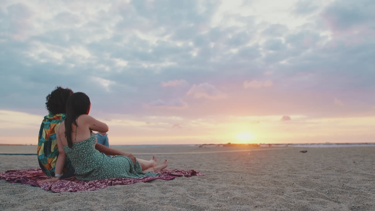 Una pareja se relaja en la playa al atardecer