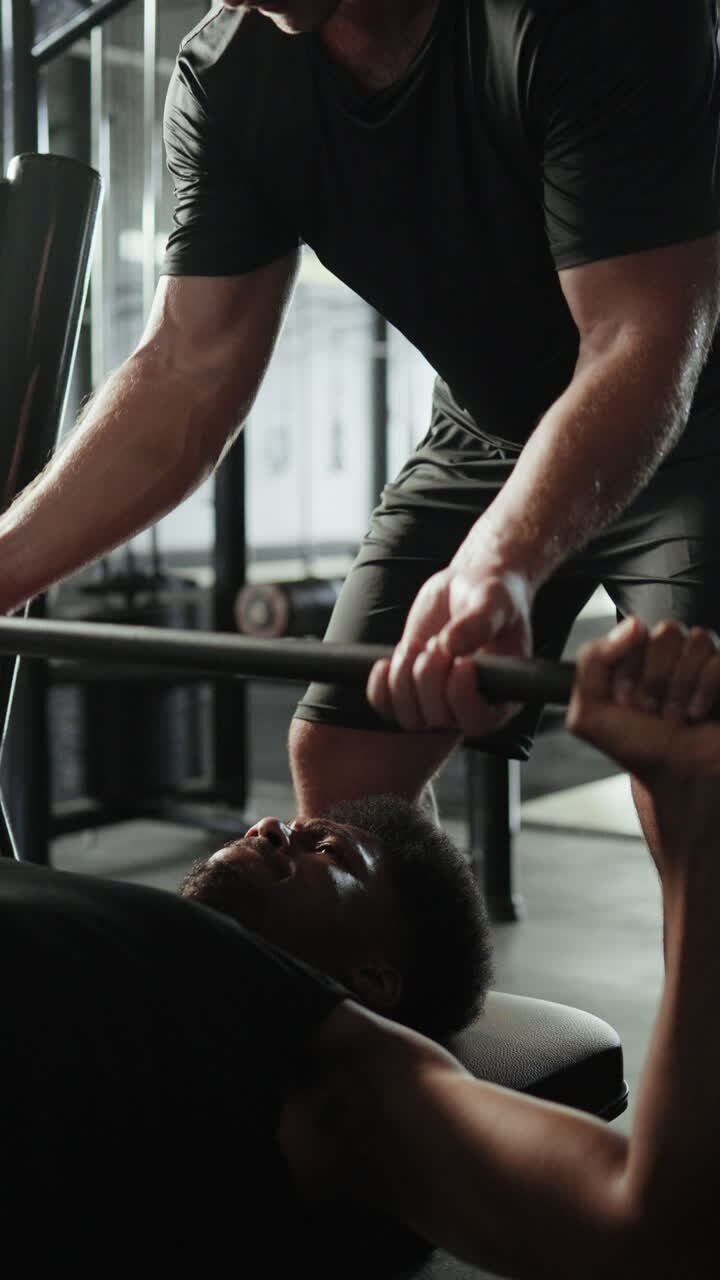 Man receiving assistance during bench press at the gym