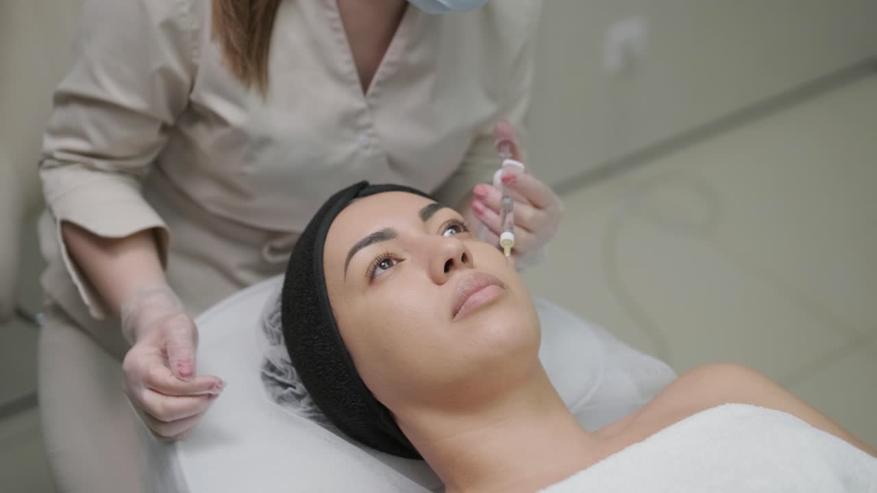 mulher fazendo terapia botulínica em clínica de cosmetologia moderna de perto. cosmetologista profissional fazendo injeção com toxina botulinica para rejuvenescimento da pele do rosto.