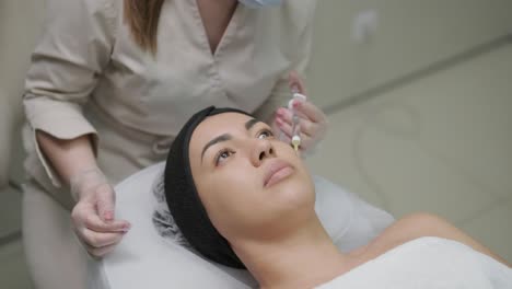 mujer haciendo terapia de botulino en una clínica de cosmetología moderna de cerca. cosmetólogo profesional haciendo inyección con toxina botulínica para rejuvenecer la piel de la cara.