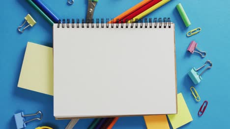 Video-of-notebook-with-copy-space-and-school-equipment-on-blue-background