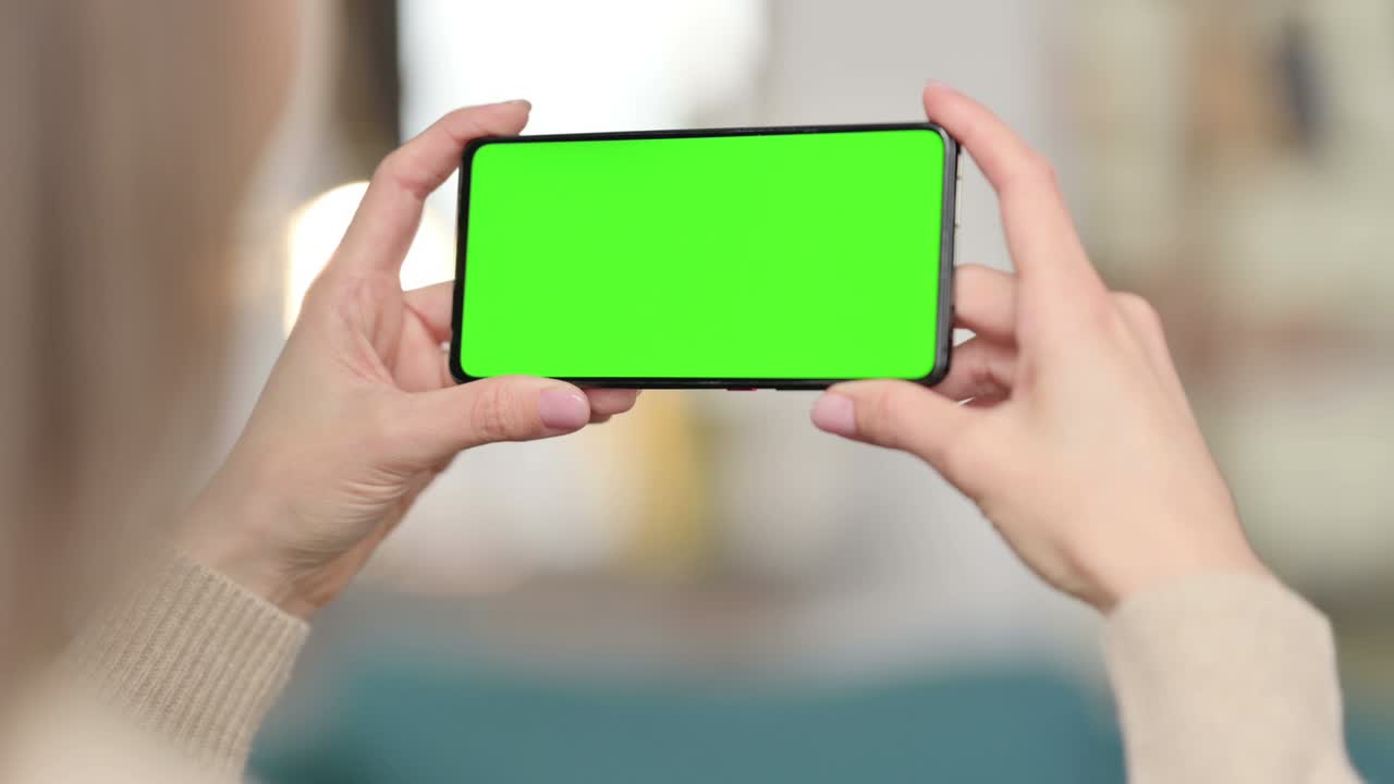 mujer mirando un teléfono inteligente con pantalla verde, pantalla cromada