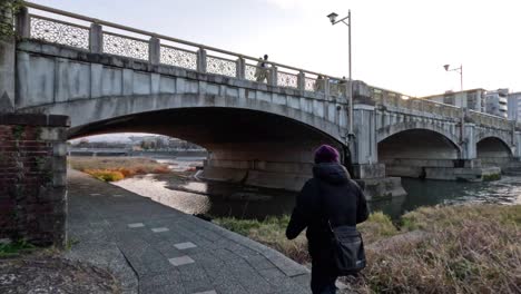 jogger and cyclist pass under bridge in kyoto