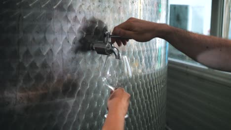 un visitante degustando vino de un barril de acero en una bodega en sinaia, rumania