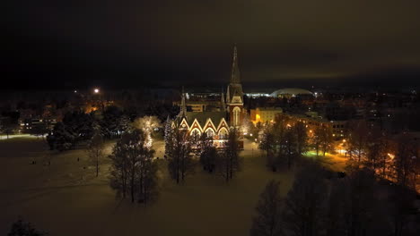 panoramic drone shot circling the lit joensuu church, winter night in finland