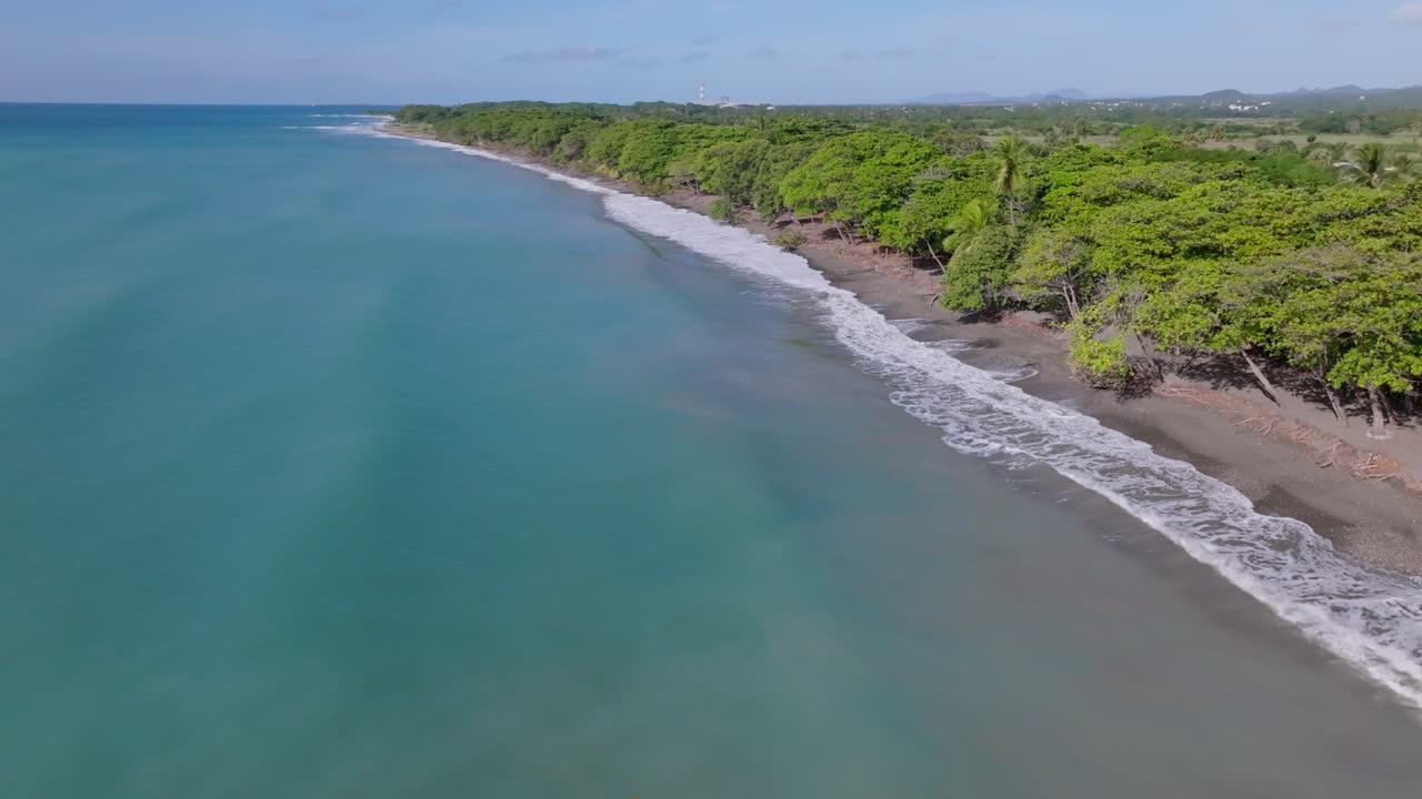Olas del océano rompiendo en la orilla arenosa de Playa Palenque con frondosos árboles verdes en verano en San Cristóbal, República Dominicana