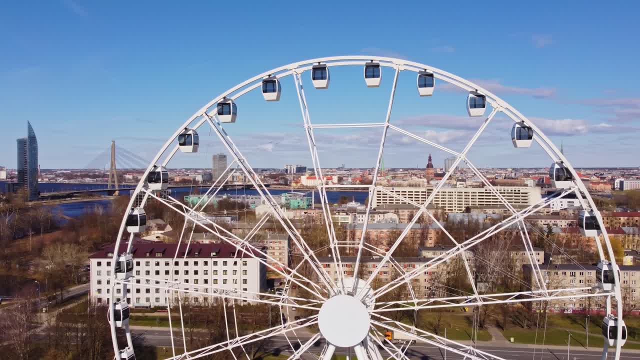 Large white Ferris wheel in Riga with cityscape, river and bridge in background