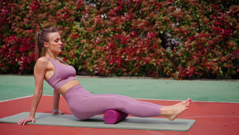 mujer realizando estiramientos de piernas con un rodillo de espuma al aire libre