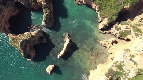 birds eye view over rugged jagged algarve coastline, in lagos, portugal - aerial top rotation shot