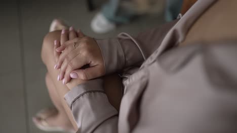 close up of woman's hands resting on her lap, wearing a light robe, showcasing elegance and calm anticipation