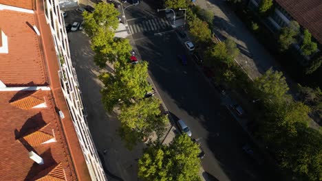 Aerial-view-of-road-in-residential-block-during-day,-cars-driving-on-the-road