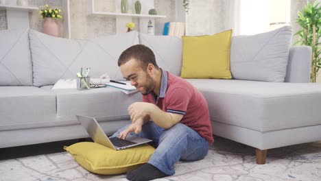 Young-male-student-with-dwarfism-studying-at-home-using-laptop.