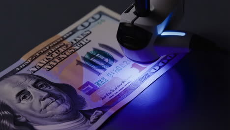 examining a one hundred dollar bill with ultraviolet light