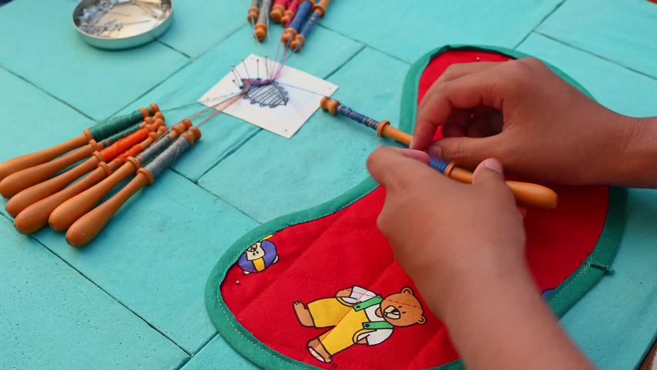 manos de niño haciendo encajes de bolillos