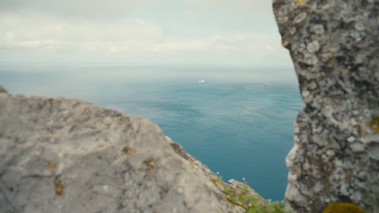 Framed view through limestone rocks on the Rock of Gibraltar overlooking the Strait of Gibraltar with distant cargo ships at sea