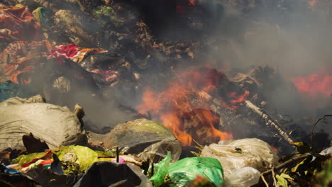 Close-up-shot-of-burning-plastic-trash-with-rising-toxic-fumes-at-sunny-day