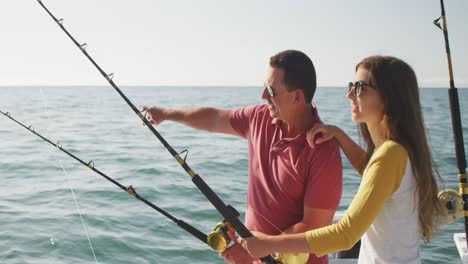 Side-view-of-a-Caucasian-man-and-his-teenage-daughter-fishing-on-boat-