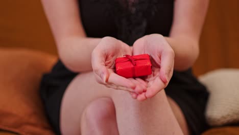 mujer mostrando un regalo de caja roja en su palma.