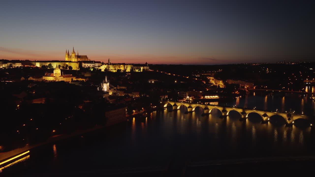 Veduta aerea notturna di Praga con Ponte Carlo, fiume Moldava e il Castello di Praga illuminato