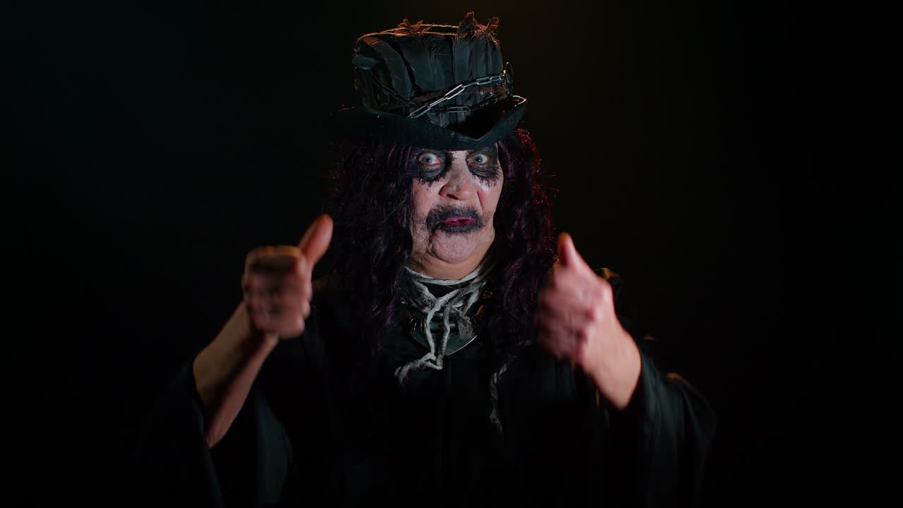 mujer mayor siniestra en disfraz de bruja de halloween mostrando los pulgares hacia abajo signo gesto de disgusto