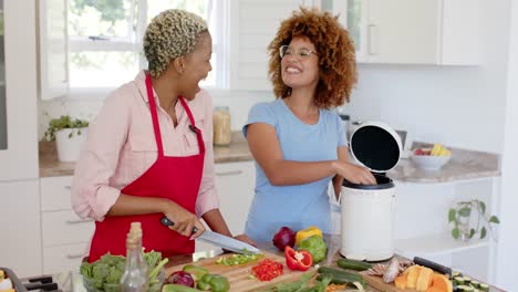 Happy-diverse-female-lesbian-couple-throwing-waste-out-and-cooking-in-kitchen-in-slow-motion