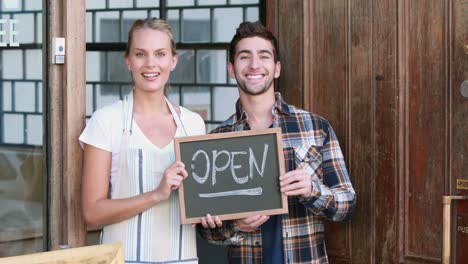 smiling waitress and hipster man holding open signboard