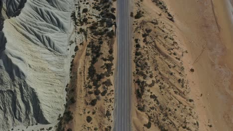 aerial view of empty costal beach road alongside weathered hillside in balochistan