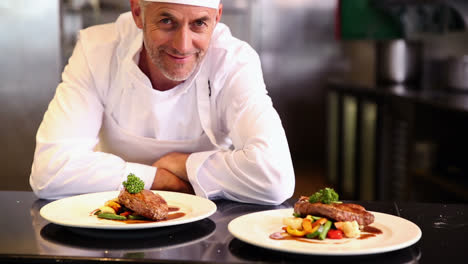 chef feliz mostrando dos platos de carne de res