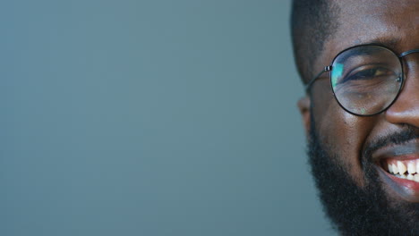 close-up view of half face of african american young cheerful man in glasses smiling joyfully at camera