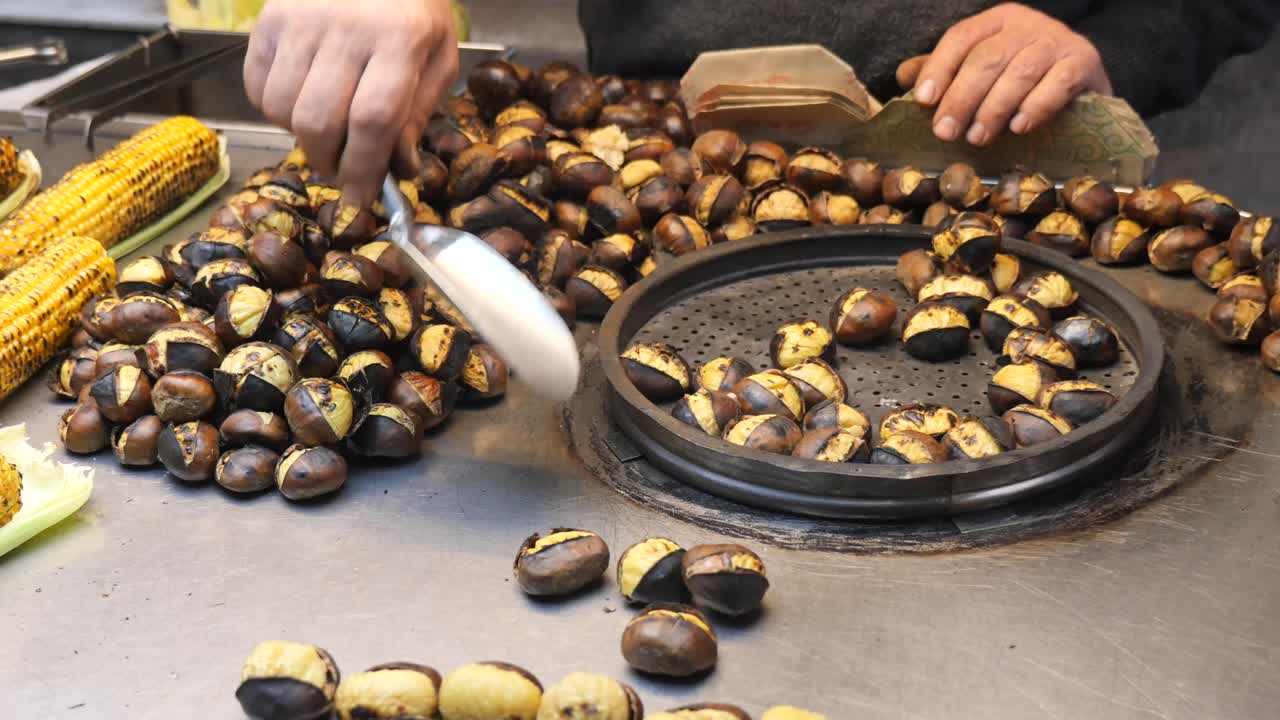 Roasted chestnuts and corn being prepared at a street food stall