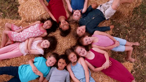 multi ethnic group of children lying in circle on straw