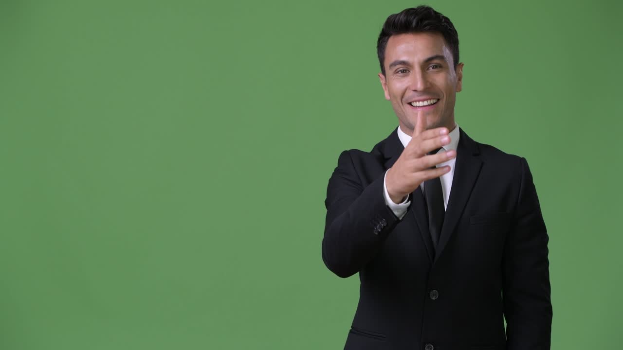 joven y guapo hombre de negocios hispano contra un fondo verde