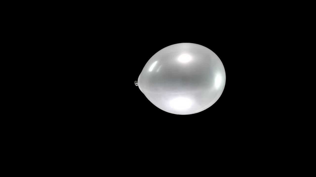 A single silver balloon floats gracefully in slow motion, descending from the top to the bottom of the display. Its reflective surface glimmers in the light, creating a tranquil, mesmerizing scene.
