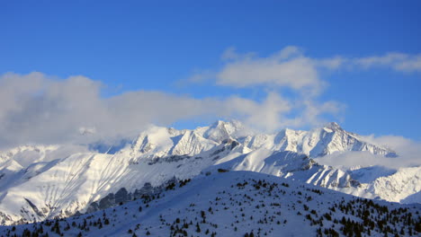 Timelapse-showing-cloud-moving-over-mountain-peaks-in-the-Mont-Blanc-area-of-the-French-Alps-in-winter,-with-blue-sky