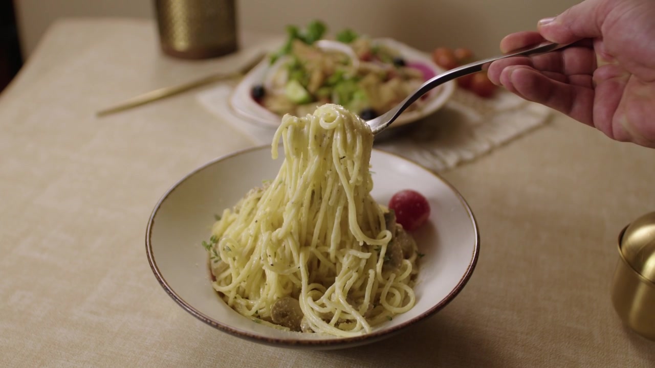 Persona che mangia deliziosi spaghetti cremosi ai funghi a cena in un ristorante.
