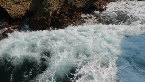 wave crashing against boulders and rocky shore