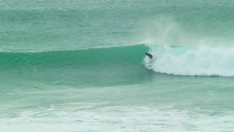 Surfer-Catches-A-Massive-Wave-At-Chapel-Porth-Beach,-Cornwall,-UK---slow-motion
