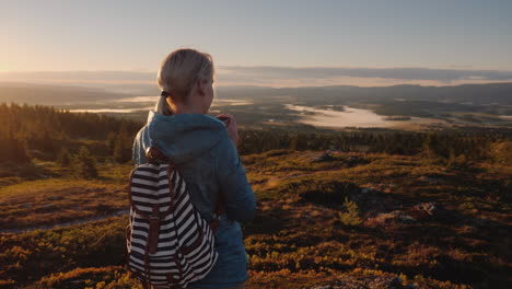 woman traveler drinks tea in a picturesque place in the mountains of norway travel and active lifest