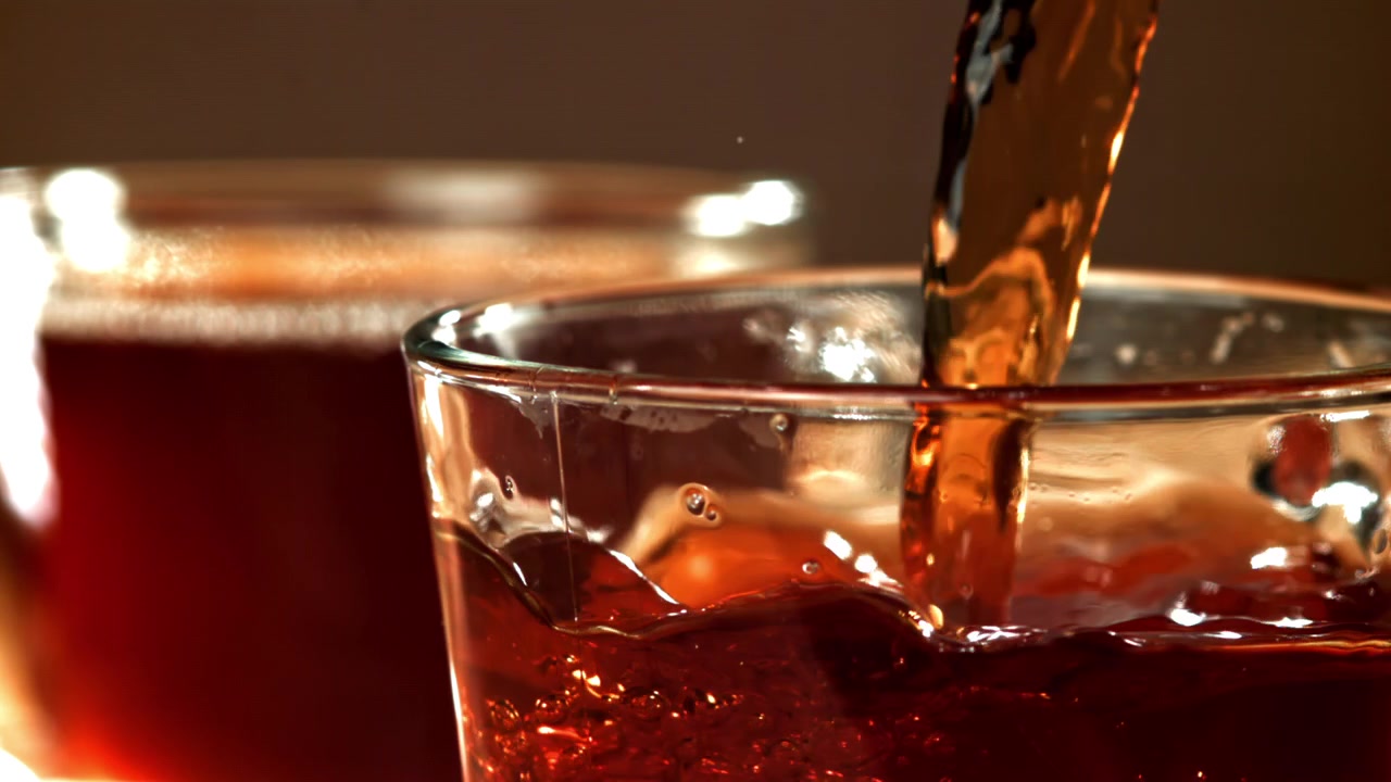 Primo piano al rallentatore di liquido scuro che si versa in un bicchiere