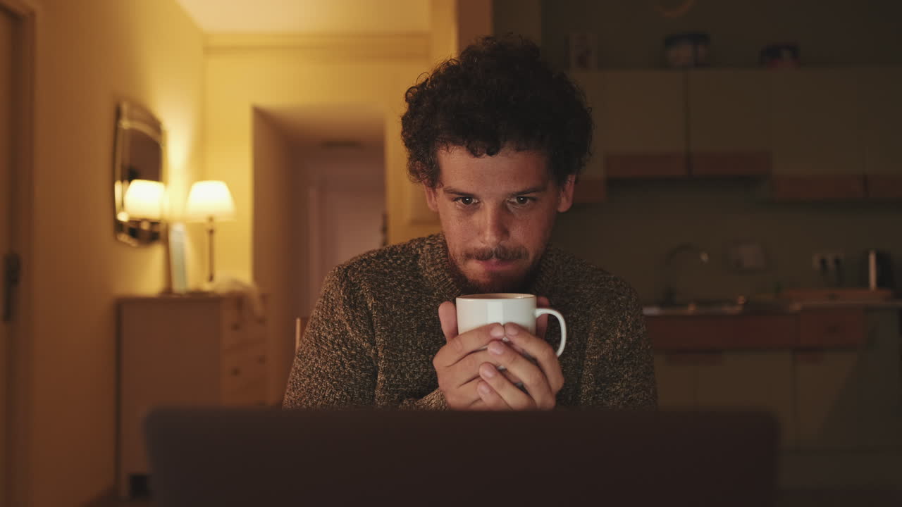 Man drinking coffee while using laptop at home